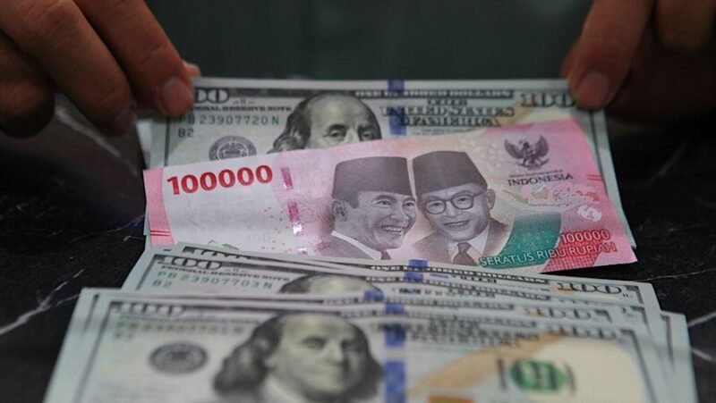 Karyawan merapihkan uang dolar AS dan rupiah di salah satu tempat penukaran uang di Jakarta.